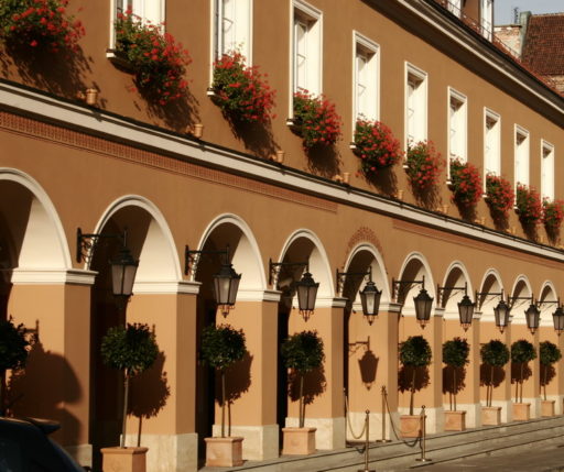 Fasada budynku z arkadami w stylu klasycystycznym, wyposażona w kinkiety 21 Leda montowane na ozdobnych, kutych wspornikach.