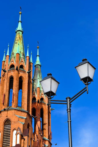 Latarnia stylowa z klasycznymi ramionami na tle kościoła